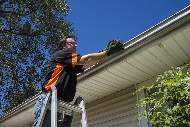 worker repairing a damaged gutter on a residential roof in Burlington, MA